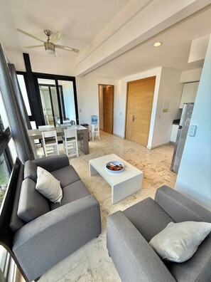 A modern living room with grey sofas, a white coffee table, and a ceiling fan.