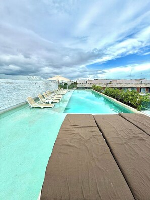 Une piscine sur le toit, dotée de chaises longues et offrant une vue sur la mer.