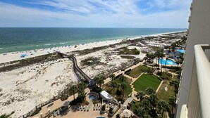 A beach resort with a pool, lounge chairs, and a boardwalk leading to the beach.