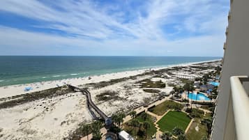 A beach resort with a pool, lounge chairs, and a boardwalk leading to the beach.