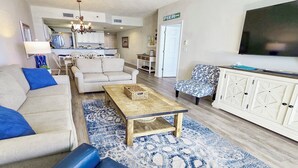 A living room with a sofa, coffee table, patterned rug, and a television.