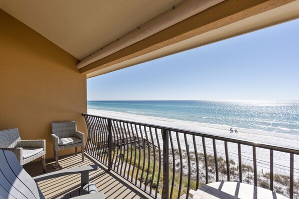 A balcony with wicker chairs and a view of the beach.