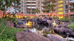 A hotel with a central courtyard featuring a water fountain surrounded by rocks and greenery. - FABULOUS OCEAN VIEW, 6th FLOOR CONDO, “165-5 STAR REVIEWS” (Lahaina)