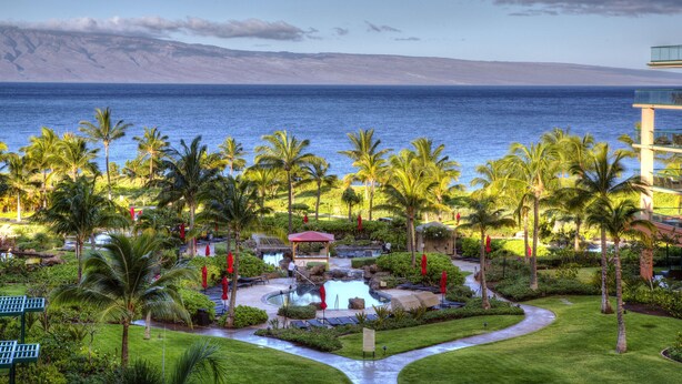 A resort with a pool, palm trees, and a view of the ocean. - FABULOUS OCEAN VIEW, 6th FLOOR CONDO, “165-5 STAR REVIEWS” (Lahaina)