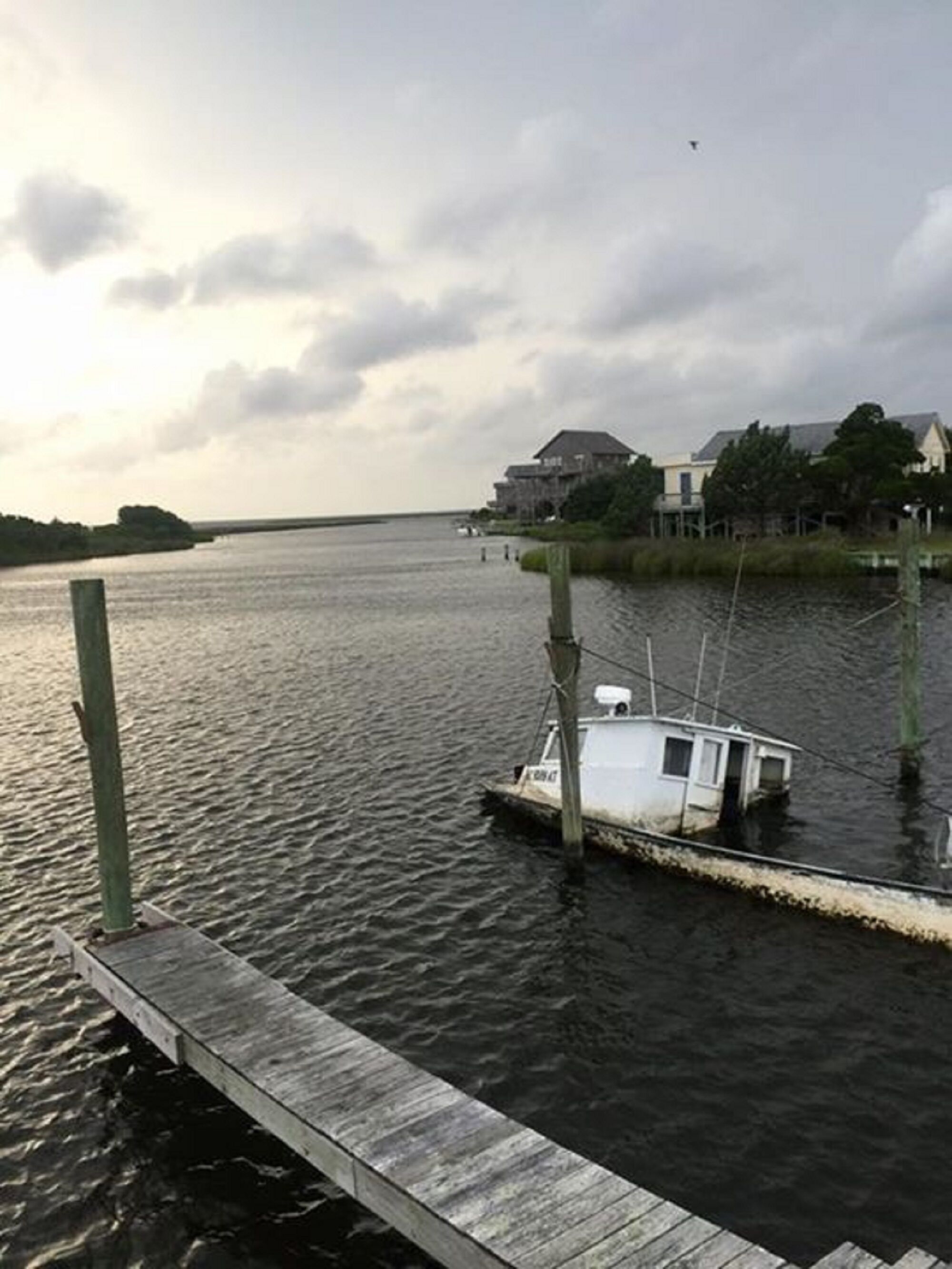 A dock with a small boat, a wooden pier, and a building in the background.