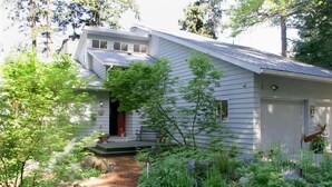 A house with a sloped roof, a front porch, and a garden with various plants and a deer sculpture. - Fir Mountain Escape - Stunning Views, River & Mountain Views, Hot Tub (Hood River)