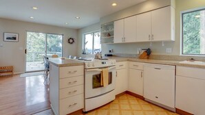 A modern kitchen with white cabinets, a built-in oven, and a dishwasher. - Fir Mountain Escape - Stunning Views, River & Mountain Views, Hot Tub (Hood River)