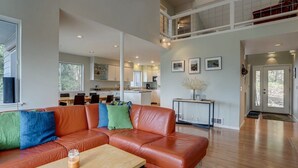 A spacious living room with a leather sectional sofa, a wooden coffee table, and a dining area in the background. - Fir Mountain Escape - Stunning Views, River & Mountain Views, Hot Tub (Hood River)