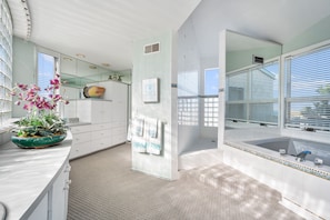 Bathroom features a large bathtub, vanity with drawers, and a mirror above the sink.
