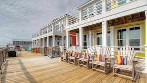 A wooden deck with Adirondack chairs and a view of a building with multiple windows.