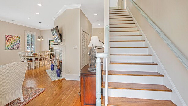 Un escalier avec des marches en bois et une rampe blanche, menant à l’étage supérieur.