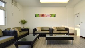 A modern living room with a sofa, two coffee tables, and a potted plant. - Hoya Resort Hotel Chiayi (Minxiong)