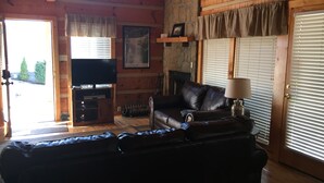 Una sala de estar acogedora con un sofá de cuero, un televisor y una chimenea.