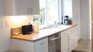 Una cucina con mobili bianchi, una macchina da caffè e una finestra.