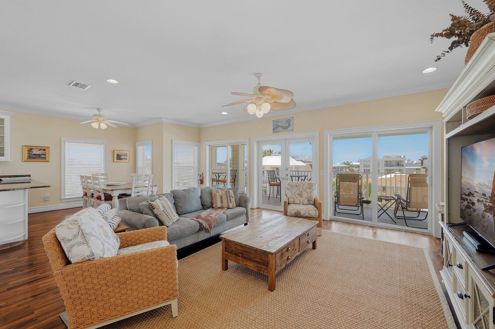 A spacious living room with a sofa, coffee table, and chairs, a dining area with a table and chairs, and a balcony with outdoor furniture.