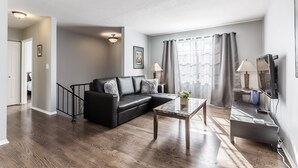 Ein modernes Wohnzimmer mit einer schwarzen Ledersofa, einem kleinen Couchtisch und einer TV-Konsole mit einem Flachbildfernseher.