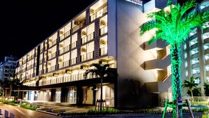 A multi-story hotel with a modern design, featuring balconies and a well-lit facade. - Cococious Monpa (Chatan)