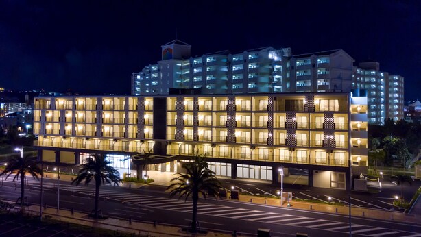 A multi-story hotel with a modern design, featuring a series of balconies and a central courtyard. - Cococious Monpa (Chatan)