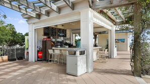 Un café al aire libre con una pérgola de madera, un cartel de menú y mesas y sillas.