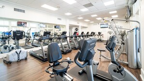 Un gimnasio con cintas de correr, elípticas y equipo de pesas.