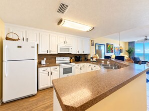 A modern kitchen with white cabinetry, a granite countertop, and a built-in oven. - Beach Club C1103 King/Qn WIFI Direct Gulf & Beach View Sleeps 4 (Gulf Shores)