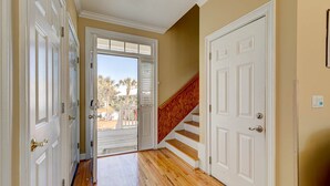 A hallway with wooden floors, white doors, and a wooden staircase.