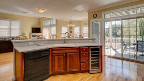 A kitchen with a large island, wooden cabinets, a dishwasher, and a wine cooler.