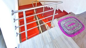 A staircase with red steps and a metal handrail, leading to a landing with a wooden ceiling and a framed picture on the wall. - Osanda Guest (Bentota)