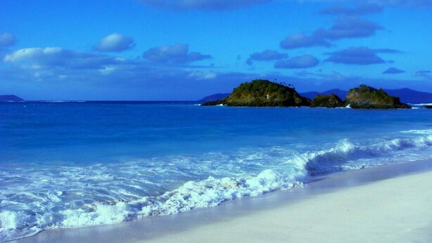 A beach with clear blue water, white sand, and small islands in the distance. - Osanda Guest (Bentota)