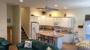 Una cucina moderna con mobili bianchi, un'isola centrale e una ventola a soffitto.