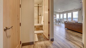 Ein modernes Interieur mit Holzboden, einem Badezimmer mit Badewanne und einer Sitzecke mit Sofa und Tisch.