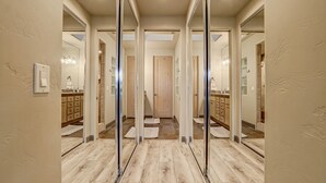 Ein Korridor mit spiegelnden Wänden, Holzboden und einer Tür am Ende.