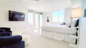 Ein Schlafzimmer mit einem Bett, einem Fernseher, einer Gitarre und einem Sessel.