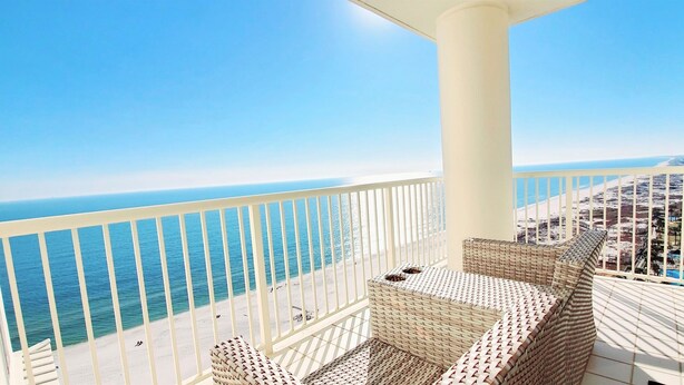 Ein Balkon mit Korbmöbeln mit Blick auf einen Strand und den Ozean.