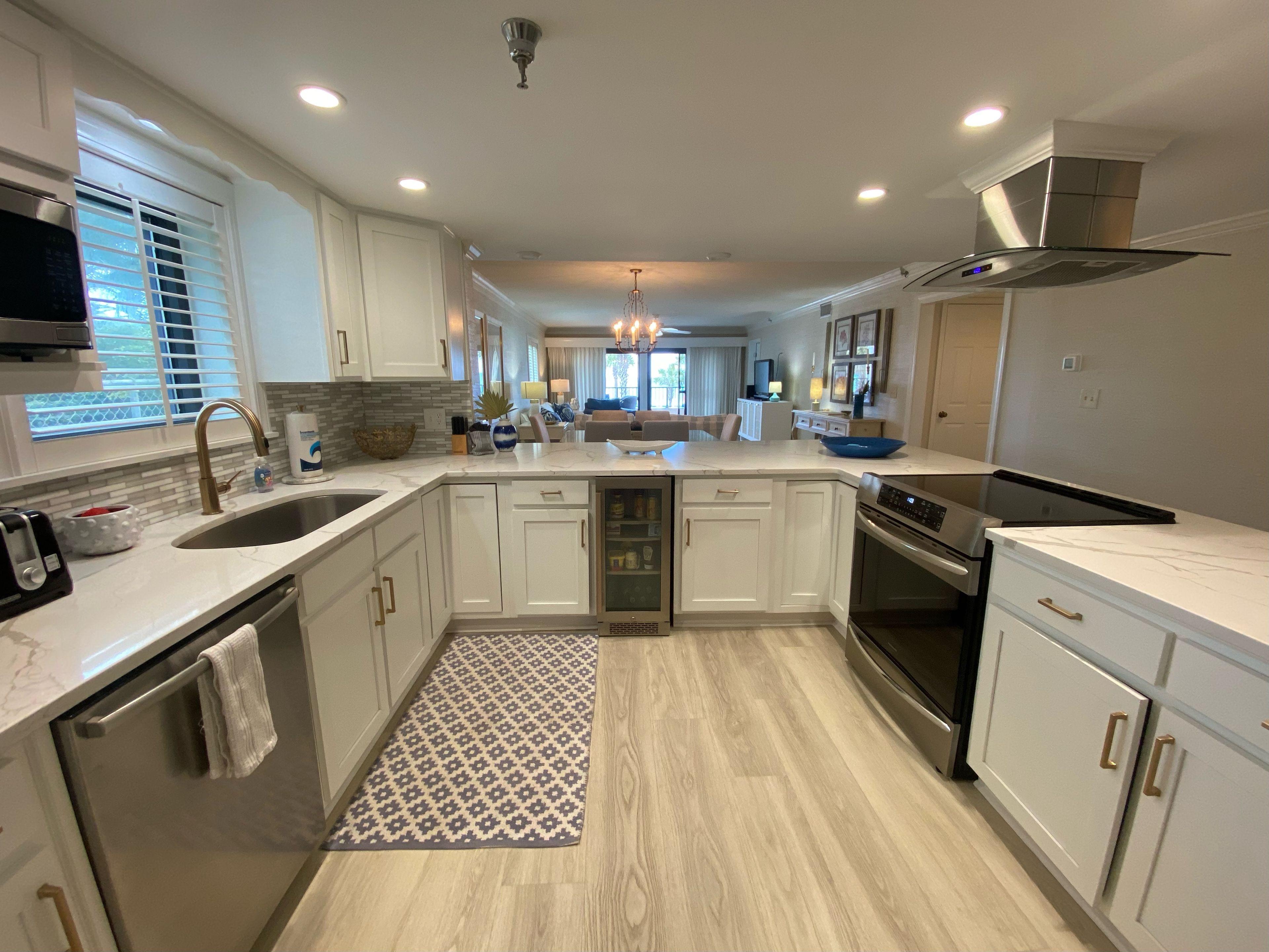 A modern kitchen with white cabinetry, a stainless steel range hood, and a built-in oven.