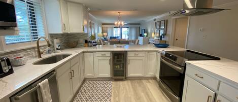 A modern kitchen with white cabinetry, a stainless steel range hood, and a built-in oven.