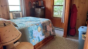 A wooden room with a bed, a desk, a ceiling fan, and a window. - Diamond Lake Island Cabin   (Cassopolis)