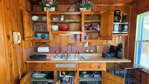A compact kitchen with wooden cabinets, a sink, and a microwave. - Diamond Lake Island Cabin   (Cassopolis)