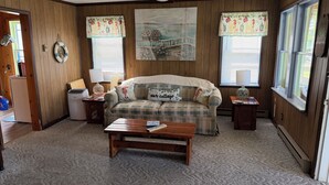 A cozy living room with a plaid sofa, a coffee table, and a painting above the sofa. - Diamond Lake Island Cabin   (Cassopolis)
