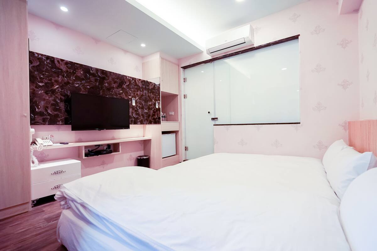 Ein Schlafzimmer mit Bett, Fernseher, Kleiderschrank und Spiegel.