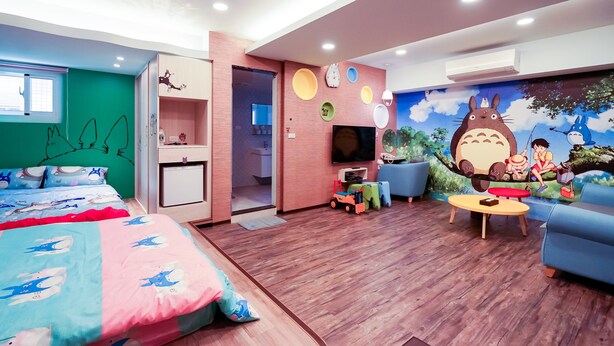 Ein Kinderzimmer mit einem Bett, einem Fernseher, einer Couch und einer Wandmalerei.