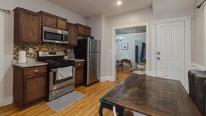 Una cocina con armarios de madera, electrodomésticos de acero inoxidable y una mesa de comedor de madera.