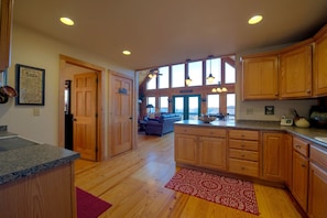 A spacious kitchen with wooden cabinets, granite countertops, and a red patterned rug.