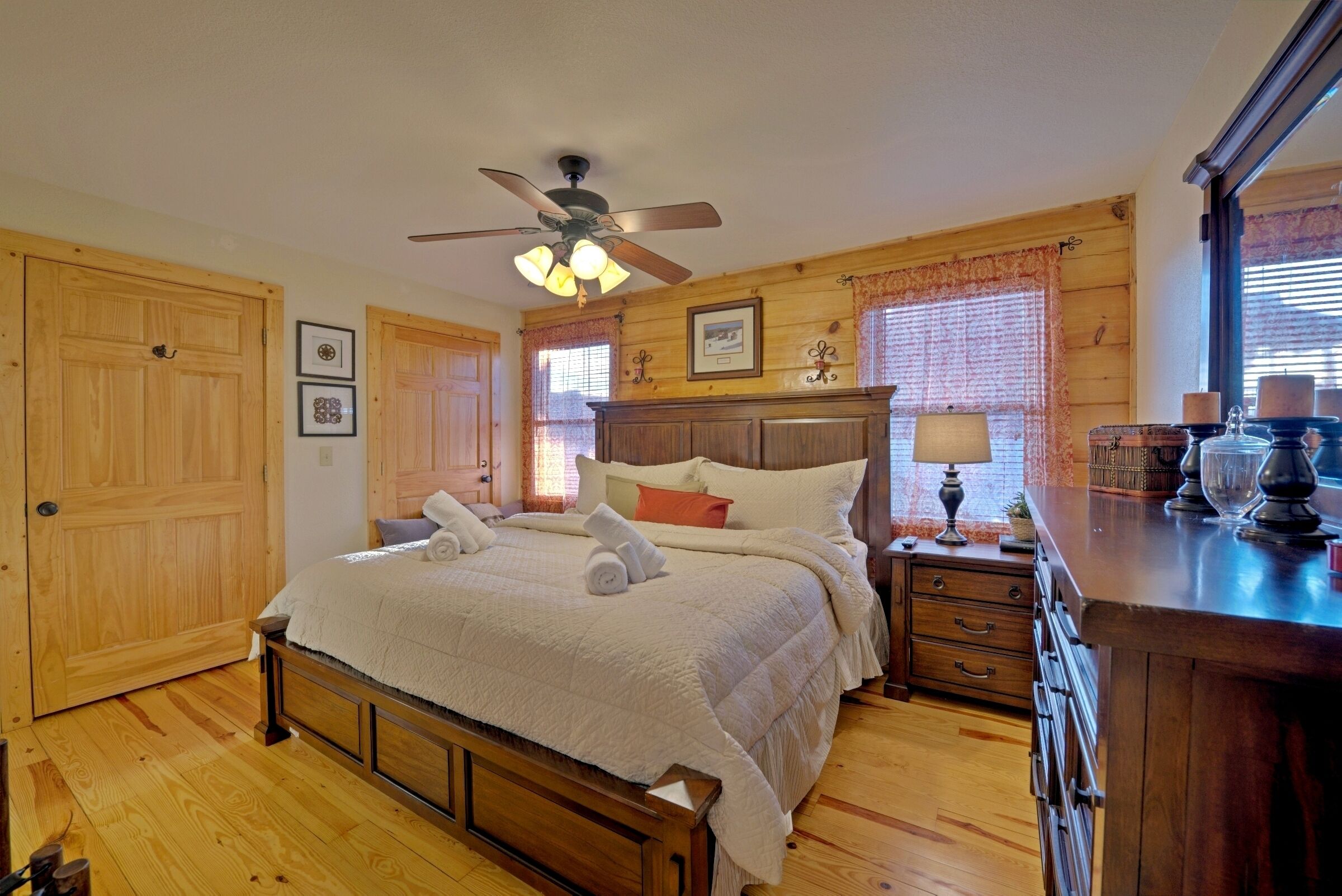 A bedroom with a wooden bed, a nightstand, a dresser, and a ceiling fan.