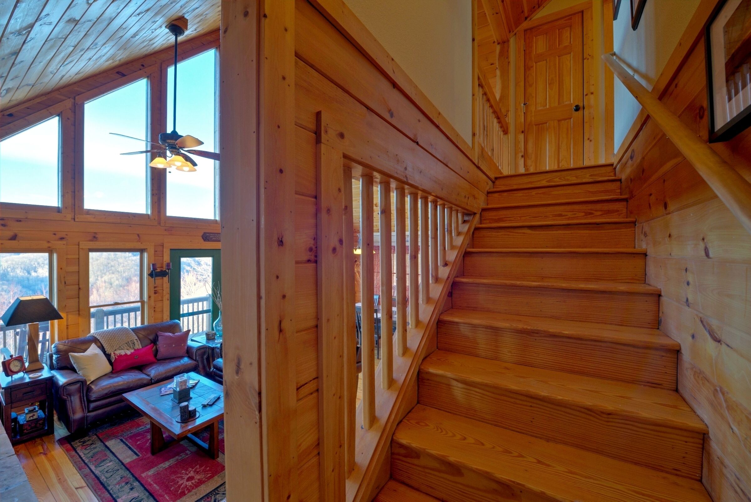 Una escalera de madera que lleva a un entrepiso con un sofá y una lámpara en la parte inferior.