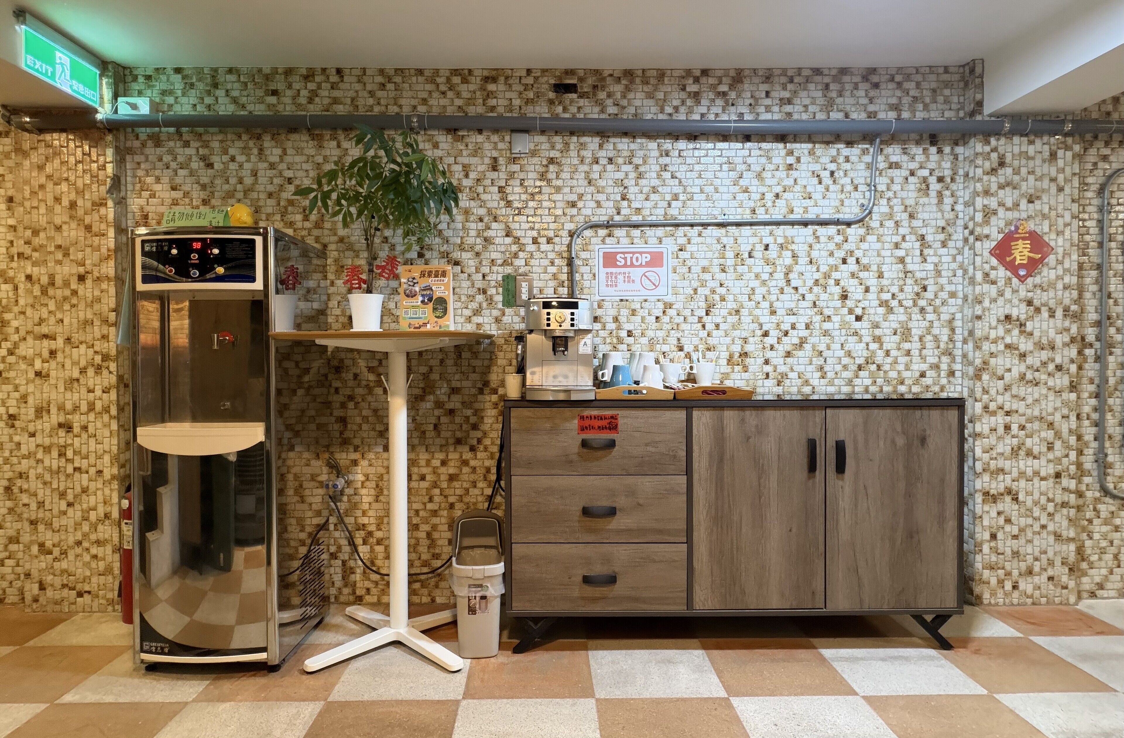 A restroom with a vending machine, a trash bin, a small table with a potted plant, and a cabinet with a 'STOP' sign.