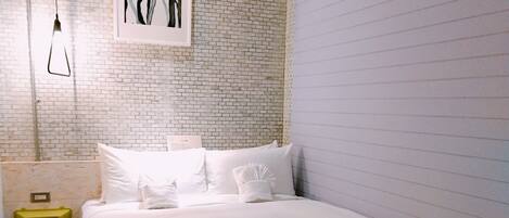 Une chambre à coucher moderne avec un grand lit, un mur décoré d’un motif en briques et un design minimaliste.