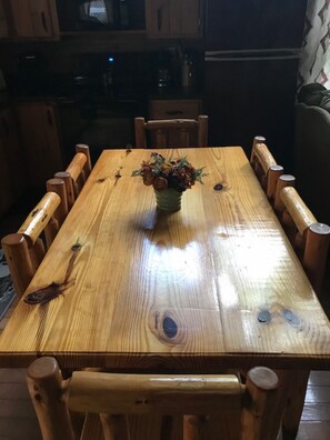 A wooden dining table with chairs, a vase with flowers, and a fish decoration. - Amazing Cabin! Easy Access! New Hot Tub! Close to all but secluded & private too (Sevierville)