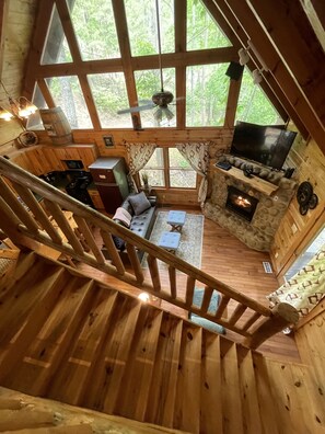 Ein Holzblockhaus mit Wohnbereich, Kamin und Fernseher.