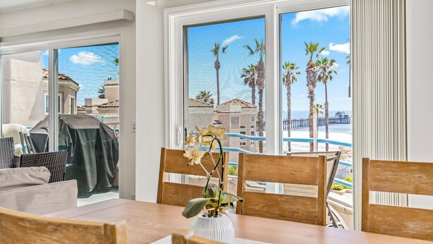 A dining area with a view of the ocean and palm trees. - Ocean Front Condo With Pool and Jacuzzi!!! (Oceanside)